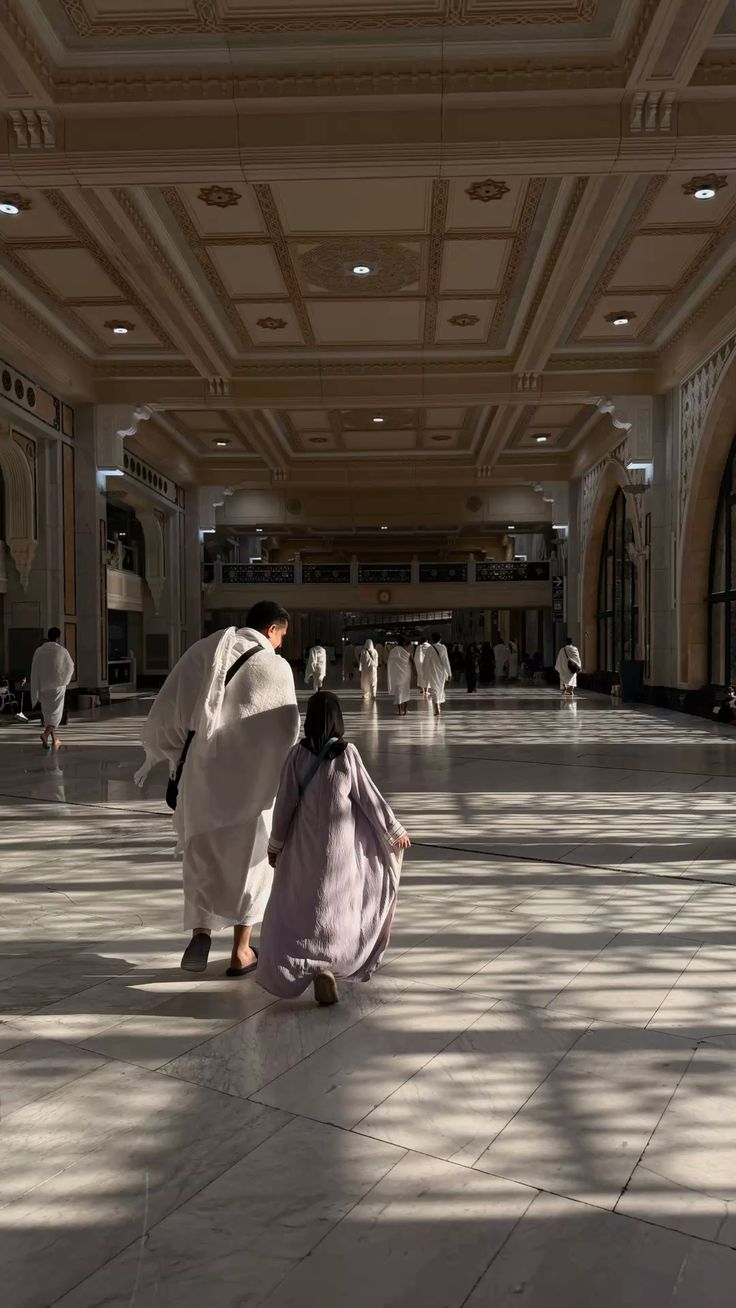 A pilgrim in ihram walking with a child through the Haram